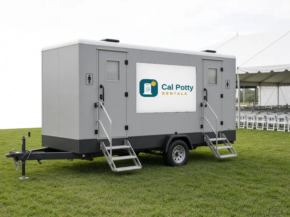 A grey restroom trailer on a lawn beside white event tents and rows of chairs